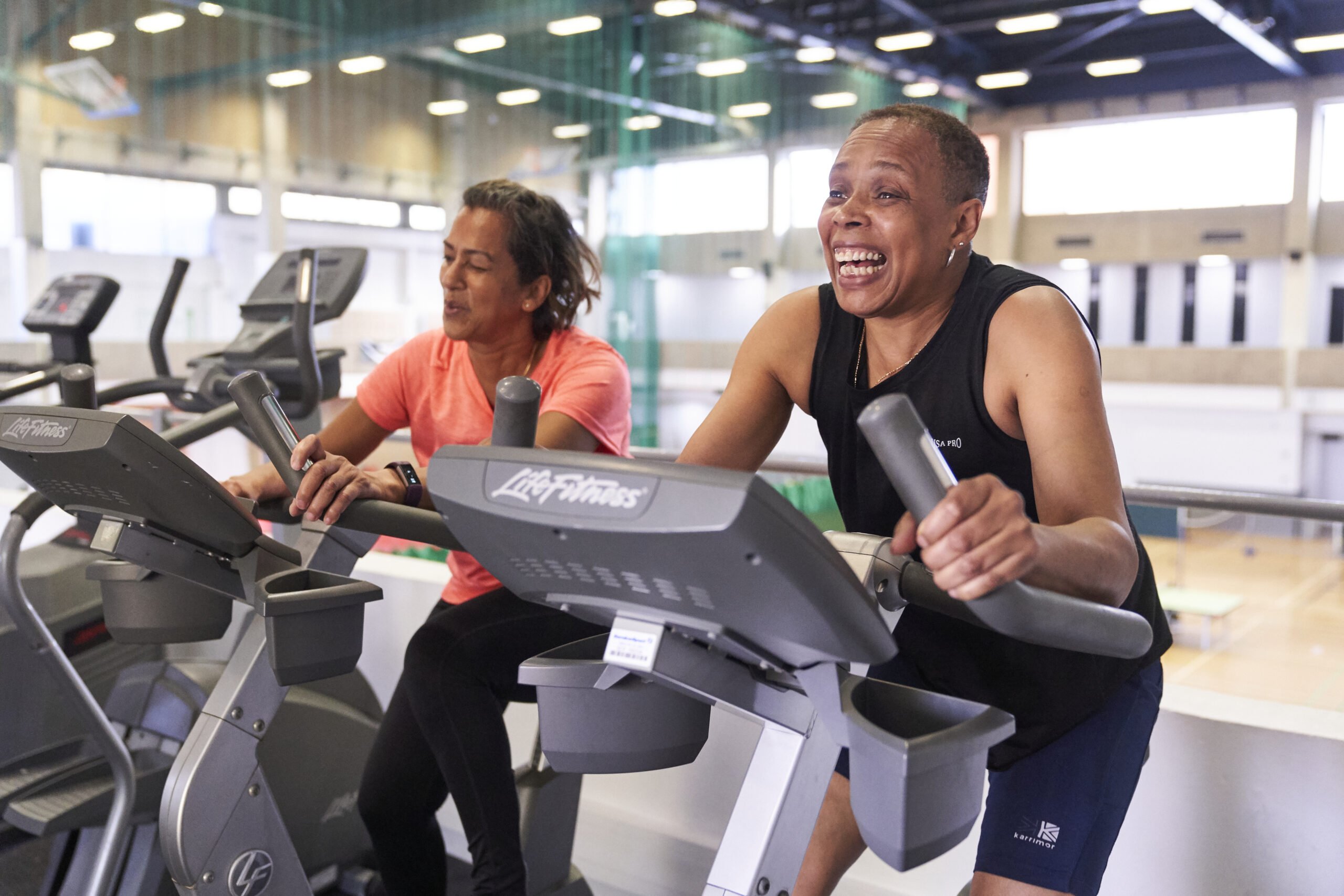 two women on spinning bikes laughing and smiling