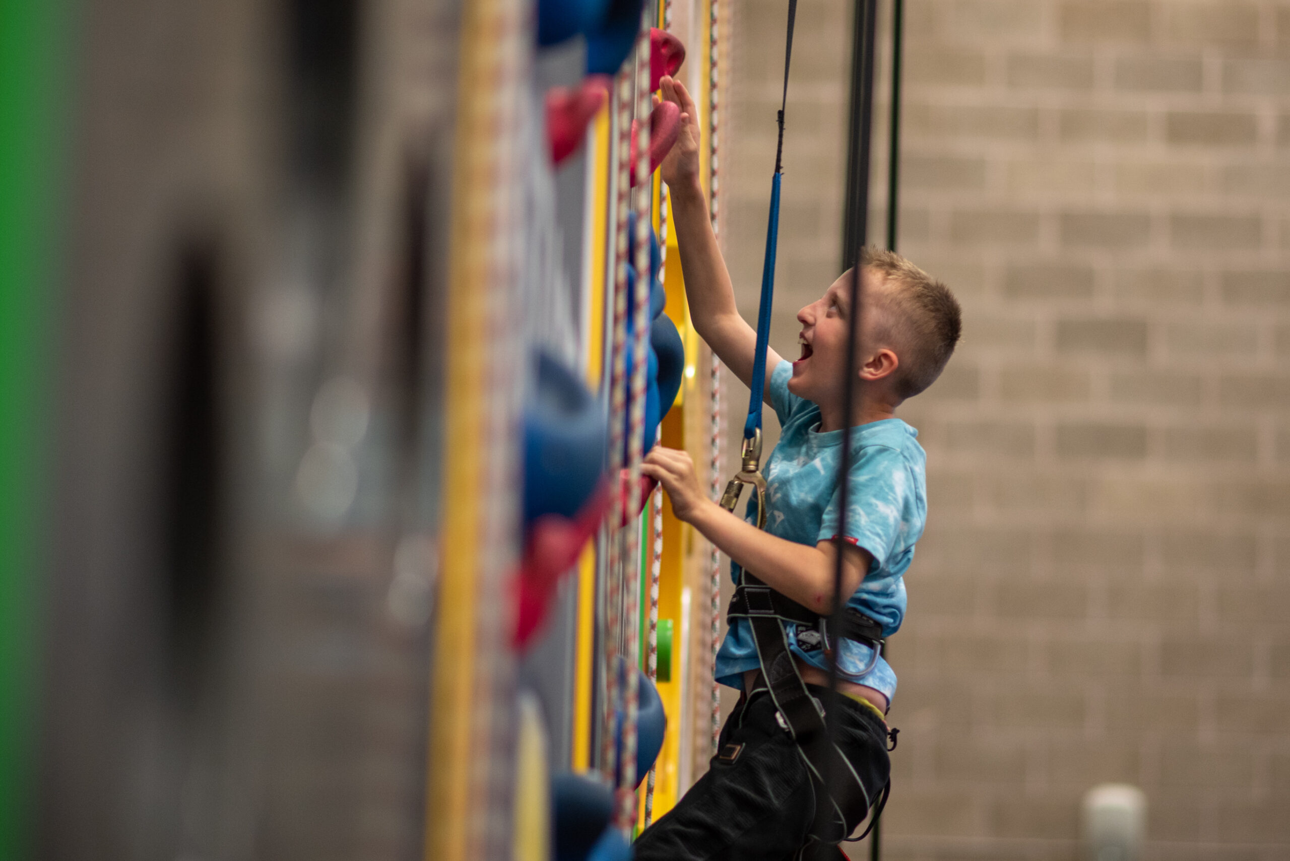 Young boy smiling whilst climbing at Active Tameside